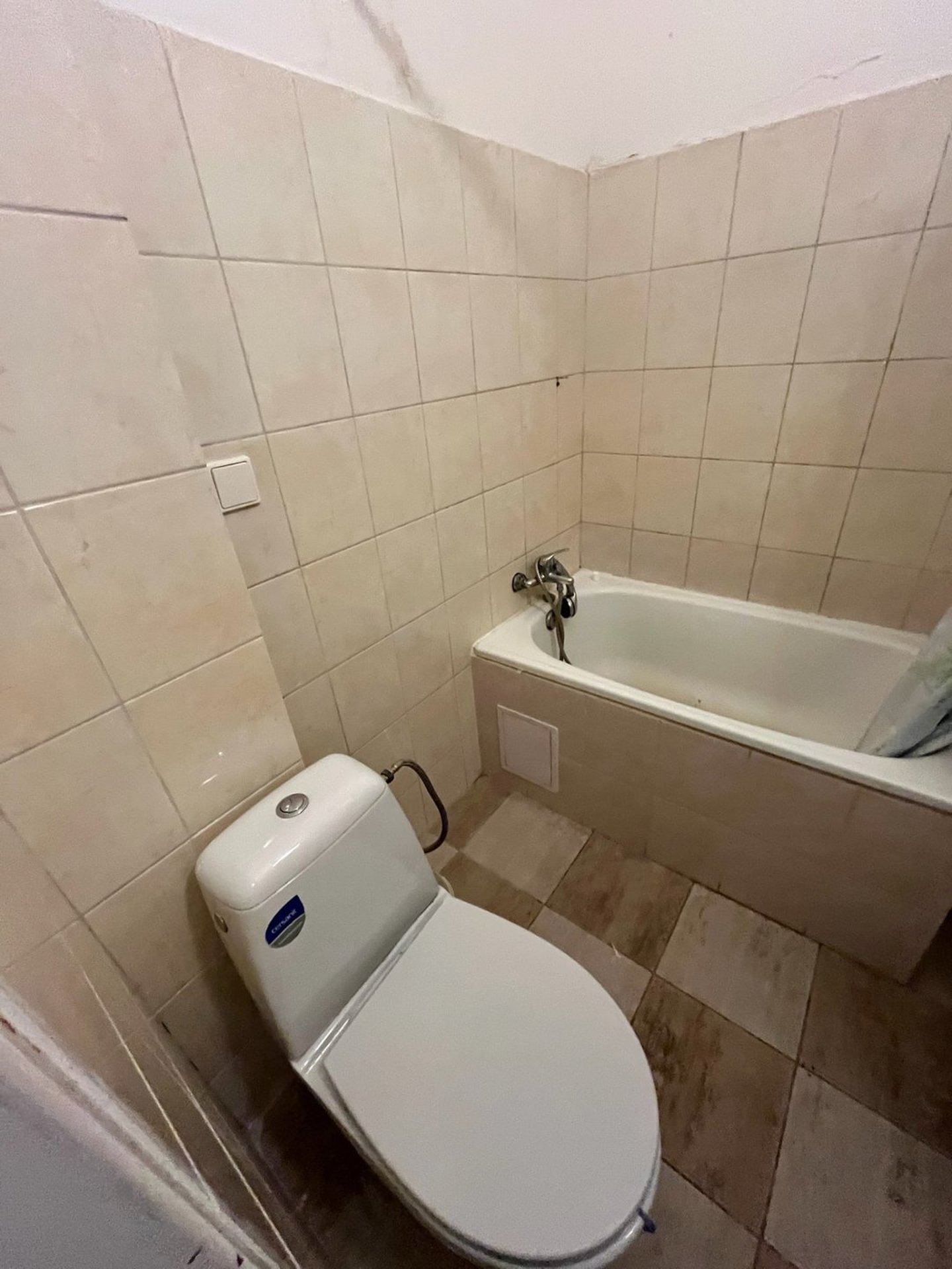 Koupelna bytu 1+kk v České Lípě před rekonstrukcí — původní WC a vana z blízkého pohledu